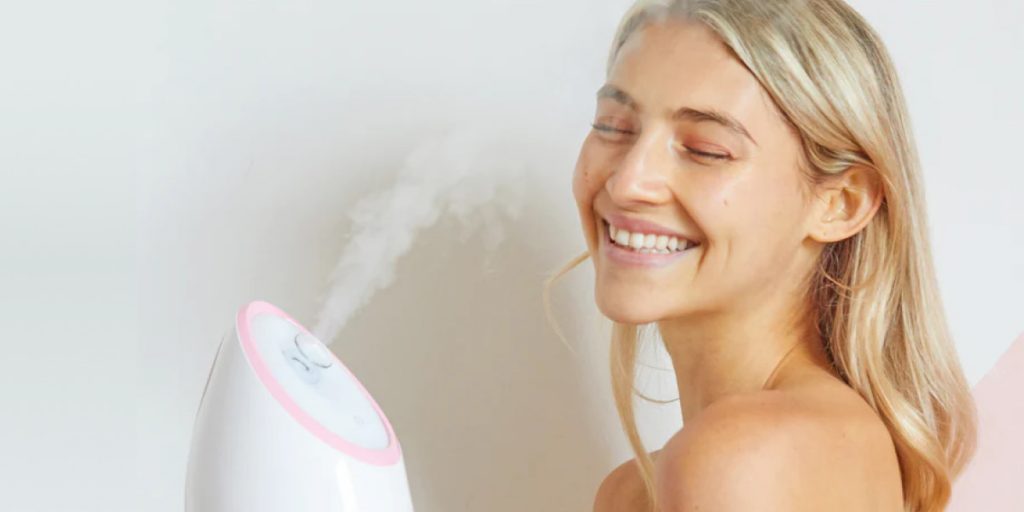 woman is smiling to facial steamer