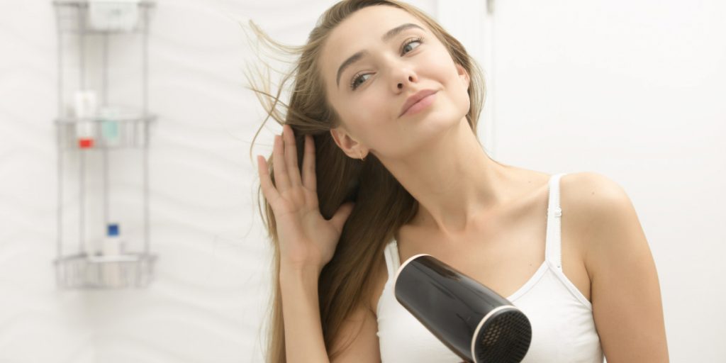 woman is drying hair with hair dryer