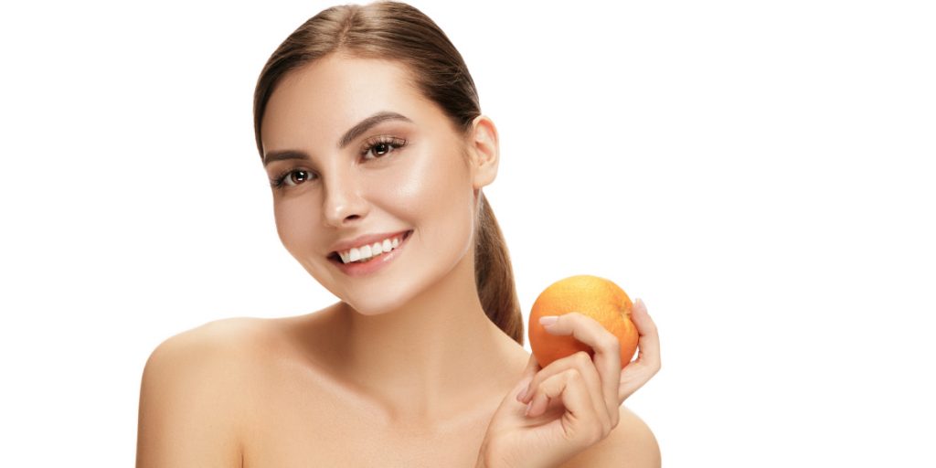 woman smiling and holding orange