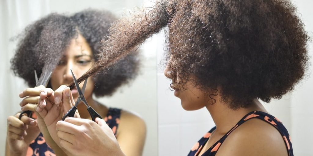 woman is trimming split ends of her curly hair