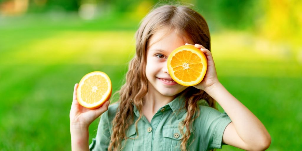 girl is holding sliced orange