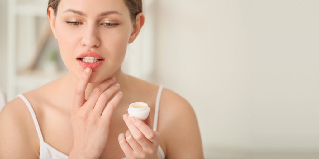 a woman is moisturizing chapped lips