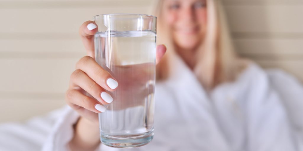 blonde is holding a glass of water