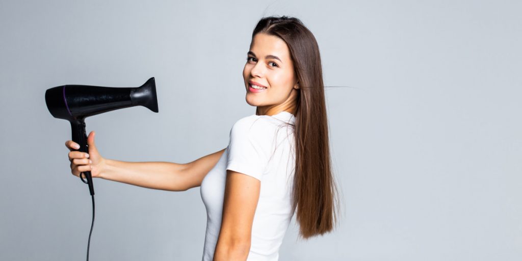 girl is drying hair with hair dryer