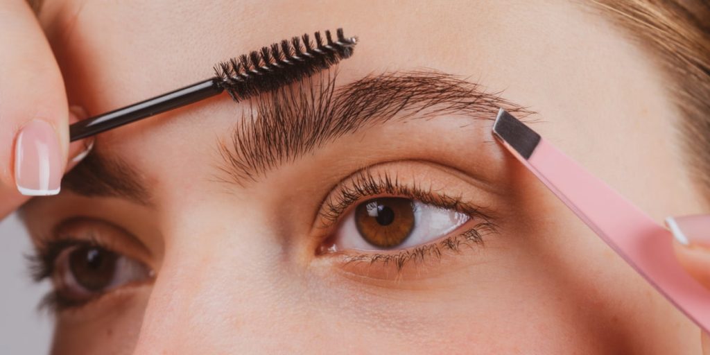 woman is trimming her eyebrow