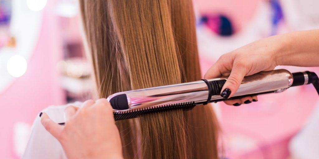 process of straightening hair with a flattening iron