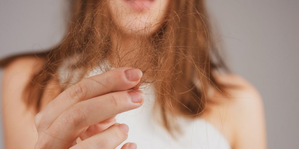 woman is holding tufts of hair