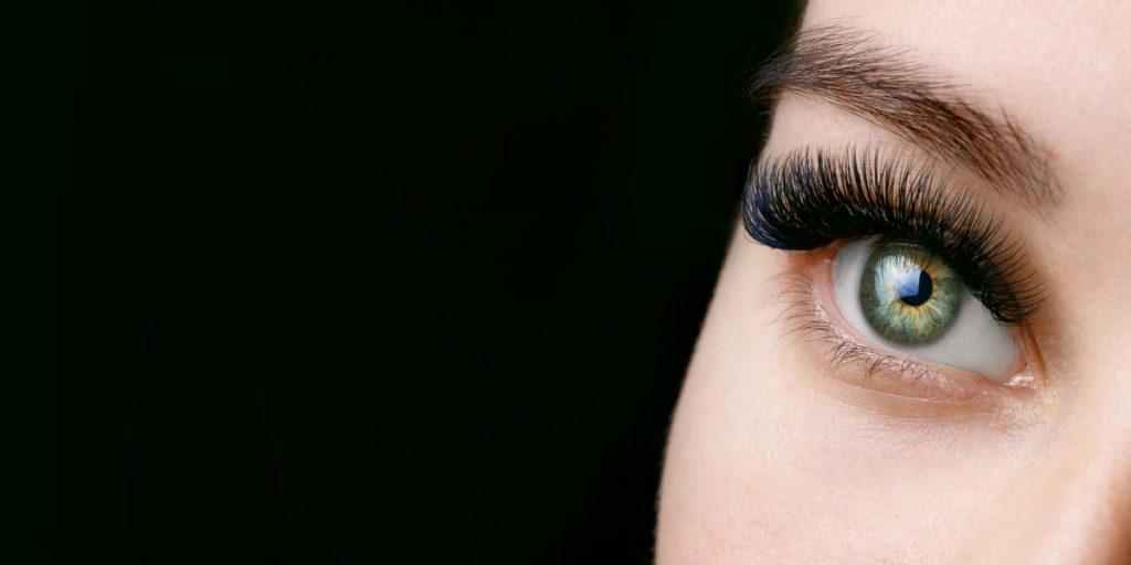 girl's green eye with eyelash extension closeup