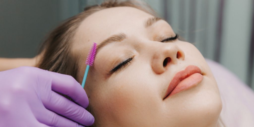 a girl is taking eyebrows waxing procedure