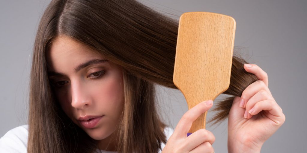 girl is combing her hair with wide comb