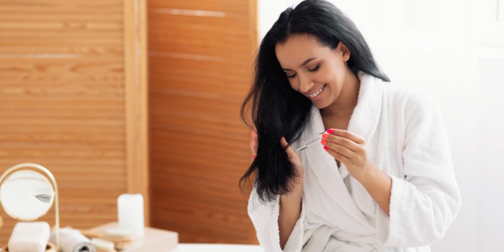 woman applies essential oil for hair growth