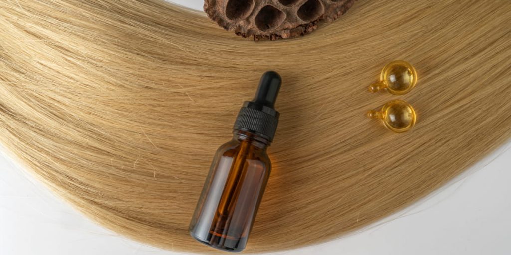 bottle of essential oil for hair and capsules on the hair