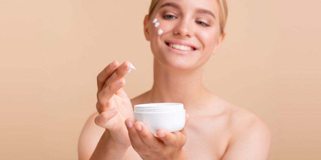 woman applyies moisturizing cream on the face